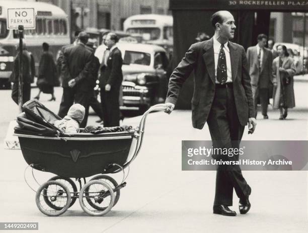 Man standing on Sidewalk with one hand on baby carriage, New York City, New York, USA, Angelo Rizzuto, Anthony Angel Collection, November 1953.