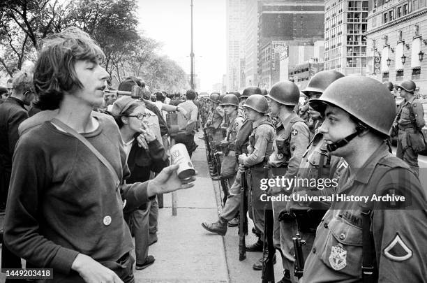 Group of People standing in front of row of National Guard soldiers, across from Hilton Hotel at Grant Park during Democratic National Convention,...