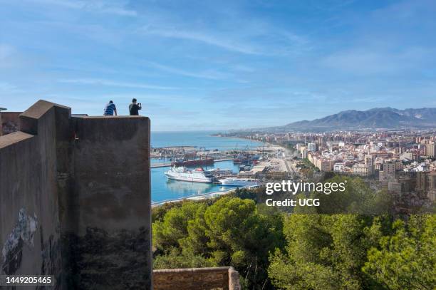 Malaga, Costa del Sol, Malaga Province, Andalusia, southern Spain. Tourists on walls of the Gibralfaro castle looking down over the city and the port.