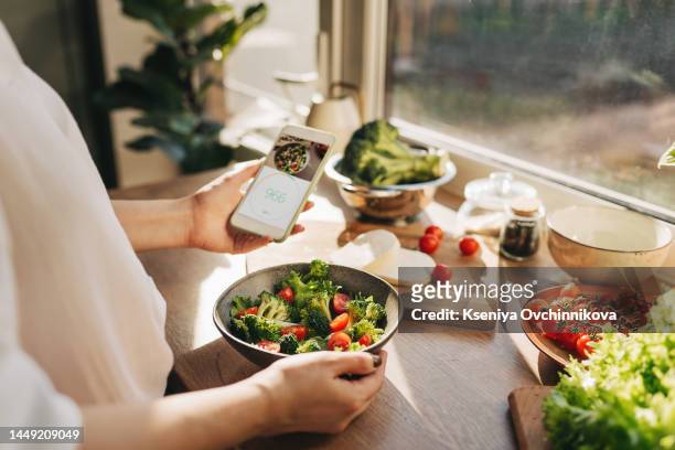 calories counting , diet , food control and weight loss concept. calorie counter application on smartphone screen at dining table with salad, fruit juice, bread and fresh vegetable. healthy eating - fat loss stock-fotos und bilder