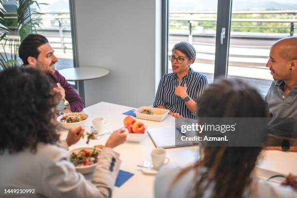 hispanic female manager explaining ideas while on lunch break - office lunch stock pictures, royalty-free photos & images