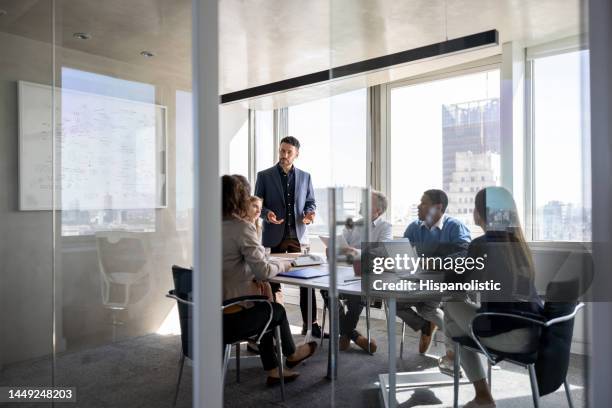 erfolgreicher geschäftsmann, der mit einer gruppe von menschen in einem meeting im büro spricht - business meeting stock-fotos und bilder