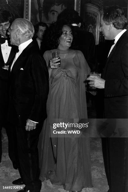 Henry Wynberg, George Cukor, Elizabeth Taylor, and Gore Vidal attend Irving "Swifty" Lazar's Academy Awards party at the Bistro Restaurant in Los...