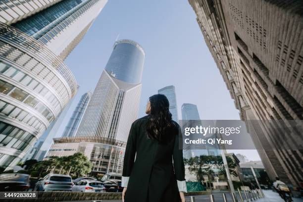 professional asian businesswoman standing in front of high-rise financial building in central business district of shanghai, china - challenge authority stock pictures, royalty-free photos & images