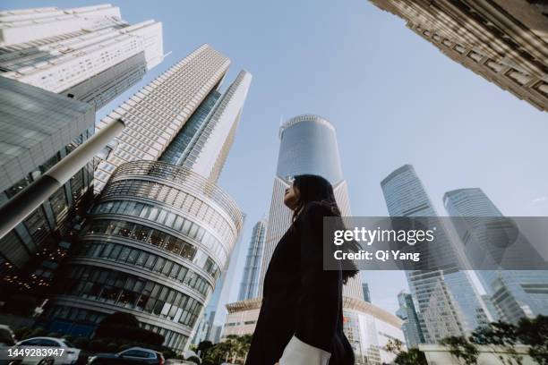 professional asian businesswoman standing in front of high-rise financial building in central business district of shanghai, china - organisation de coopération de shanghai fotografías e imágenes de stock