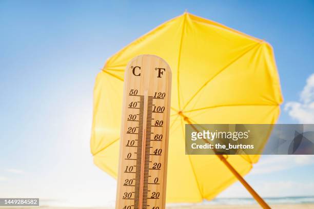 thermometer at beach against yellow parasol - heat haze stock pictures, royalty-free photos & images