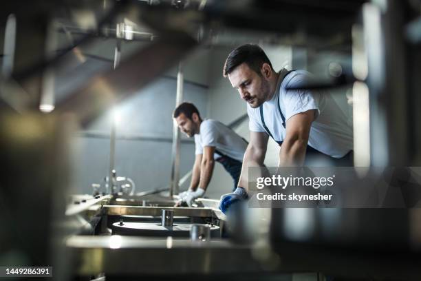 arbeiter, die an einer maschine in einer fabrik arbeiten. - maschinenbau stock-fotos und bilder