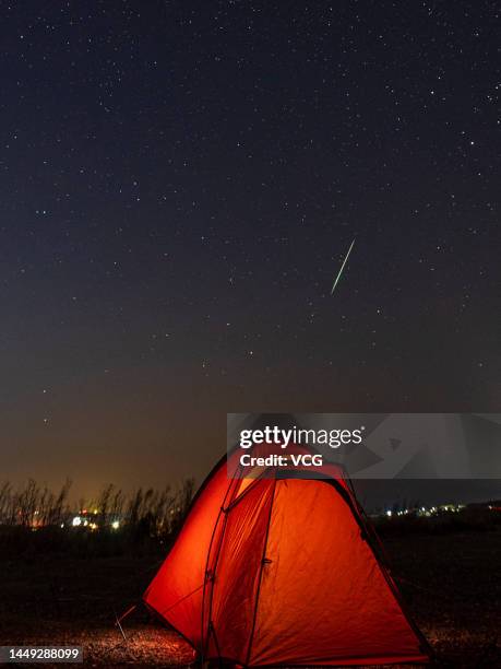 Meteor of Geminid meteor shower streaks across the night sky over a camp on December 14, 2022 in Qingdao, Shandong Province of China.