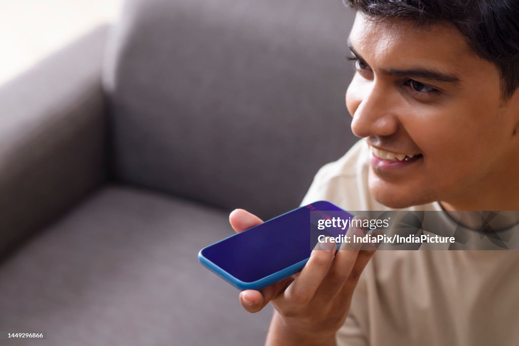 Close-up of young man talk with virtual digital voice recognition assistant