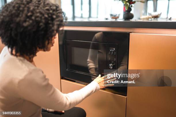belle femme hispanique utilisant un micro-ondes au bureau - microwave photos et images de collection