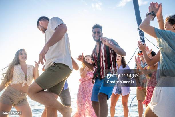 freunde tanzen auf einem segelboot - blue shorts stock-fotos und bilder