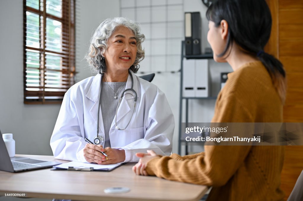 Professional female doctor is talking to and diagnosing a young patient in the clinic