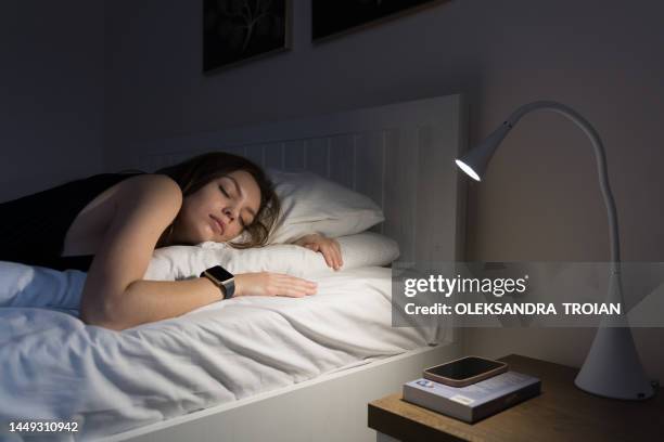 young woman sleeping with smart watch tracker at night - dormir fotografías e imágenes de stock