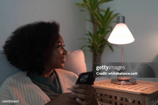 happy woman using smart phone controlling appliance. - telephone switch stockfoto's en -beelden