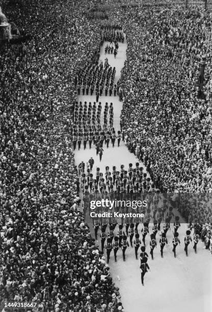 Crowds of people look on as Grenadier Guards of the British Army march down the Place de la Concorde to take the salute during the Bastille Day...