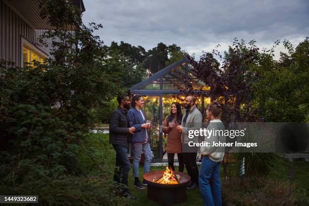 happy friends talking in garden - brazier stock pictures, royalty-free photos & images