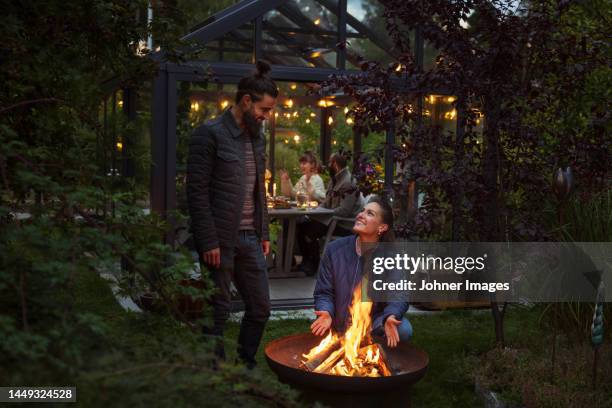 friends sitting at fire in garden - brazier stock pictures, royalty-free photos & images