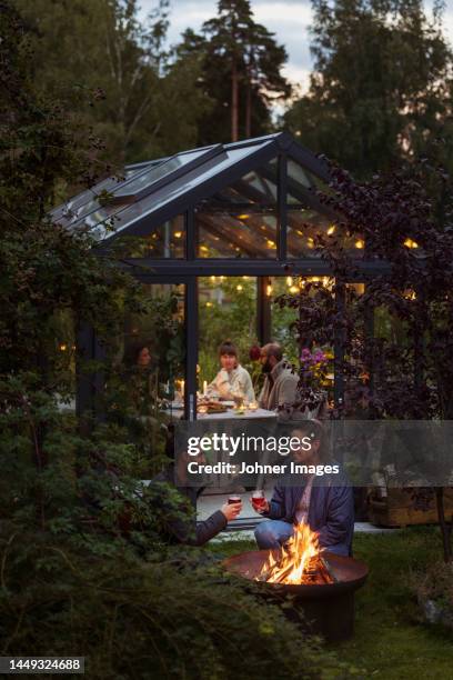 friends sitting at fire in garden - brasero photos et images de collection