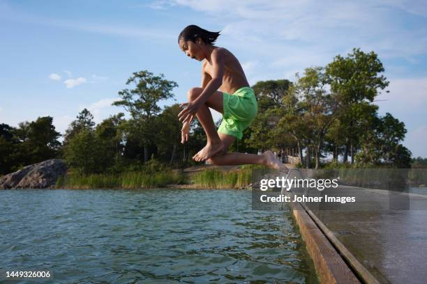 boy jumping into water - bathing jetty stock pictures, royalty-free photos & images