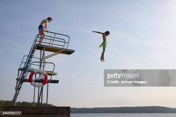teenage boys jumping into water from jumping tower - hopptorn bildbanksfoton och bilder