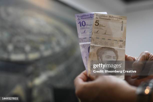 a person holding venezuelan banknotes - bolívar venezuelano sovrano foto e immagini stock