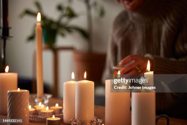 woman sitting at home with lit candles - kaarslicht stockfoto's en -beelden
