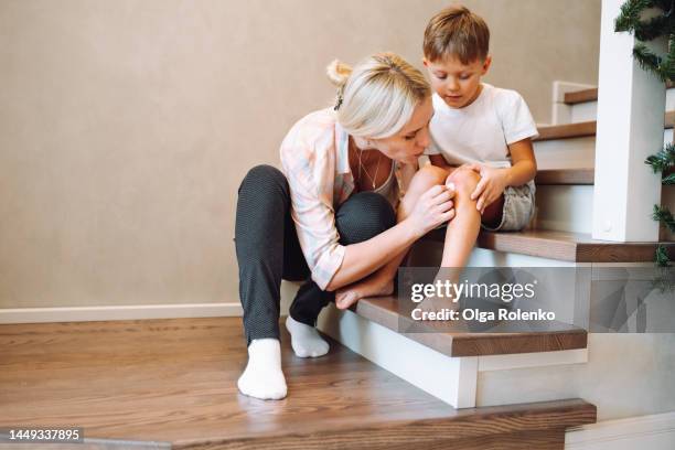 little boy knee damage. mother curing and disinfecting knee wound of little son - wundversorgung stock-fotos und bilder