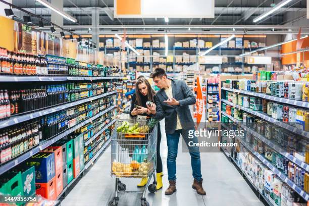young couple shopping together at the grocery store - inexpensive stockfoto's en -beelden