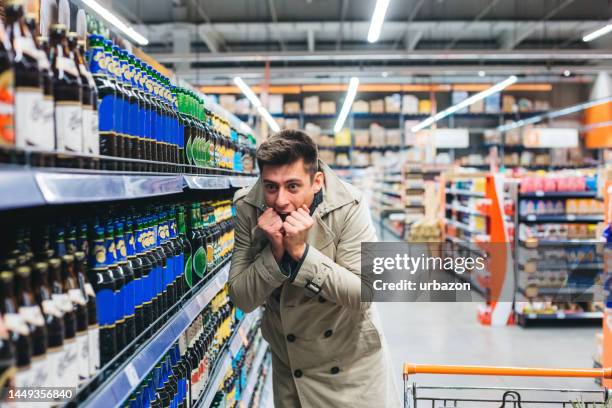 junger mann begeistert davon, ein bier im supermarkt zu kaufen - buying beer stock-fotos und bilder