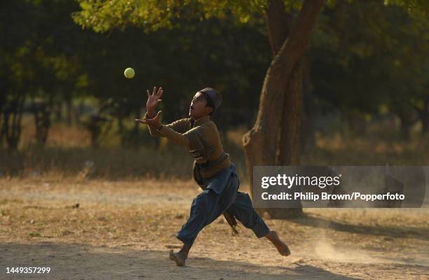 Mohammad Sarfraz, 12 years old attempts to catch a ball on a patch of ground as boys play cricket near Jinnah International Airport on December 15,...