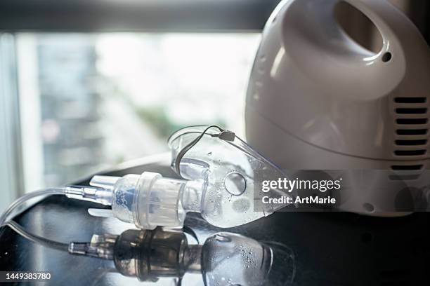 vernebler mit gesichtsmaske auf einem tisch im innenbereich - inhalator stock-fotos und bilder