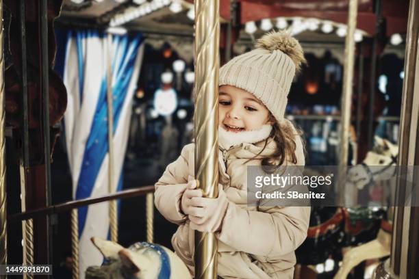 smiling girl enjoying carousel horse ride at christmas market - noel sapin stock-fotos und bilder