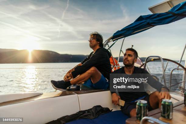 vater und sohn segeln auf einem segelboot - father son sailing stock-fotos und bilder