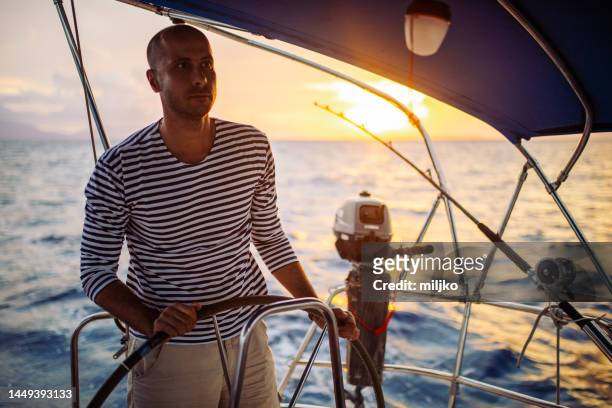 hombre navegando al atardecer - camisa a rayas fotografías e imágenes de stock