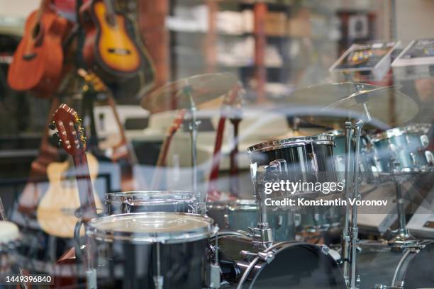 musical instrument shop window. blurred background. drum kit in the foreground - musical instrument shop foto e immagini stock