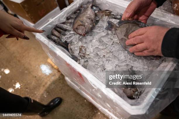 Woman points to a fish being handled during the early hours of the morning at The Fulton Fish Market in Hunts Point on December 15, 2022 in the Bronx...