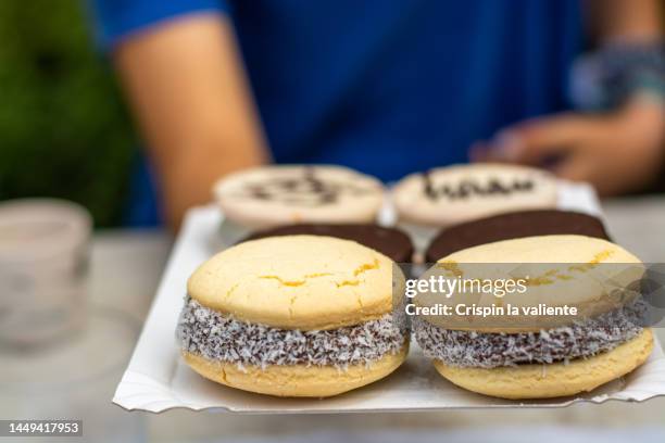 woman's hand offering a tray with alfajores cookies - alfajores foto e immagini stock