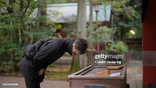 male tourist visiting shrine and praying - tokyo temple stock pictures, royalty-free photos & images