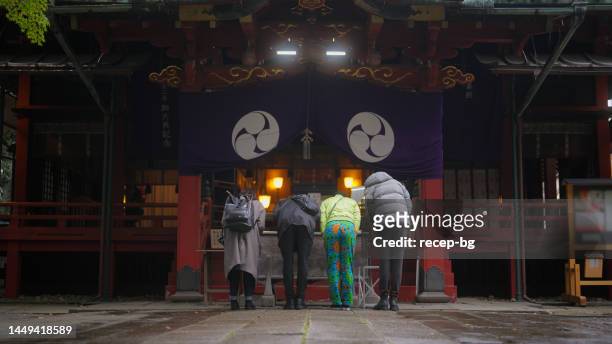 gruppe multirassischer freunde, die den schrein besuchen und beten - shintoismus stock-fotos und bilder
