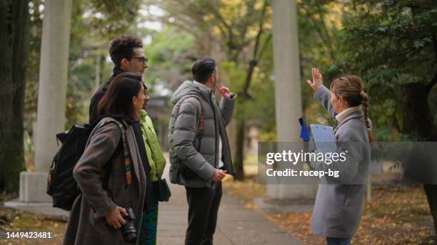 tourist guide guiding group of multiracial friends to shrine and teaching them about shrine - guidebook stock pictures, royalty-free photos & images
