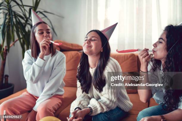 mujer sonriente recibiendo cuernos de fiesta de cumpleaños tocados por amigos - matasuegras fotografías e imágenes de stock