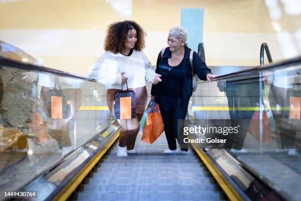 mutter und tochter auf rolltreppe im einkaufszentrum - lupus stock-fotos und bilder