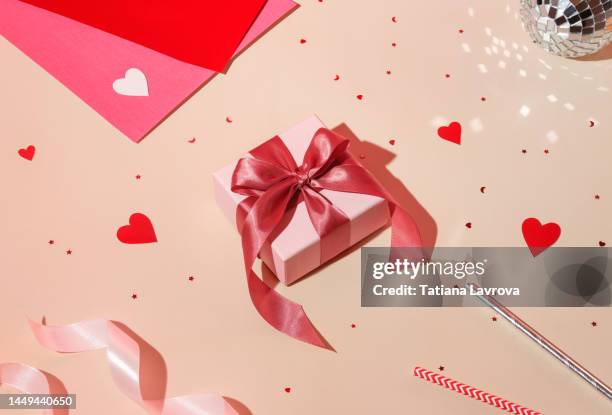 valentine day composition concept: white gift box with magenta colored bow, red hearts confetti and pink paper on pastel background. high angle view, flat lay - gift ストックフォトと画像