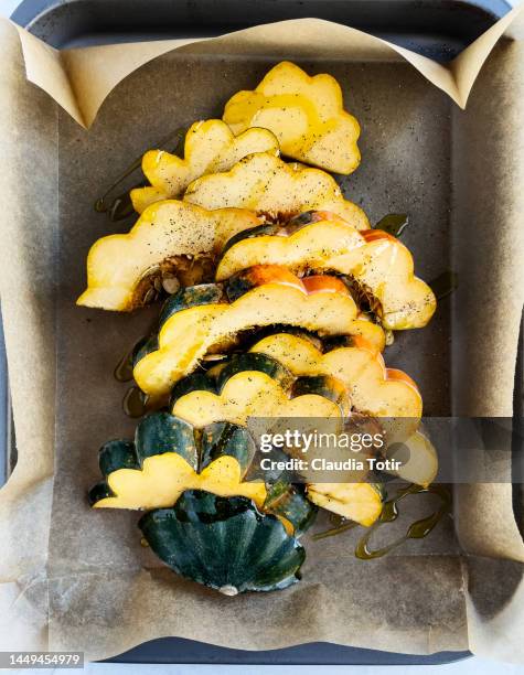 slices of acorn squash on a tray on parchment paper - acorn squash stock pictures, royalty-free photos & images