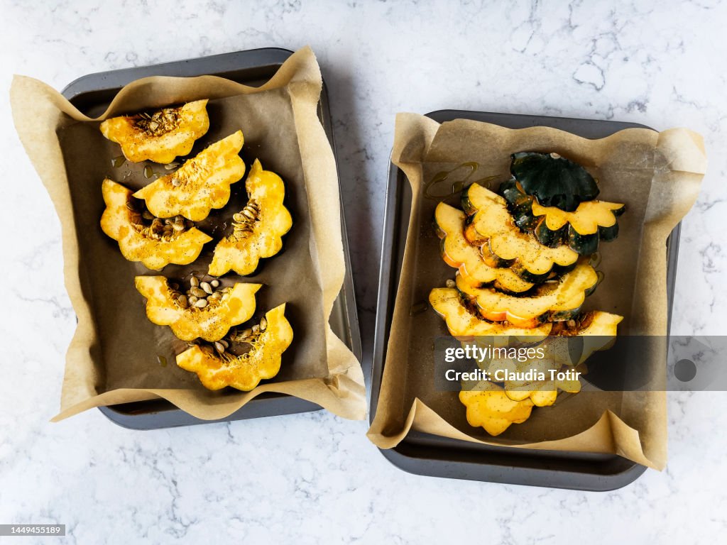 Two trays of sliced acorn squash on white background