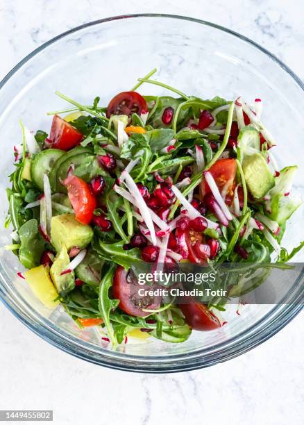 glass bowl of fresh salad with pomegranate seeds on white background - rucola stock-fotos und bilder