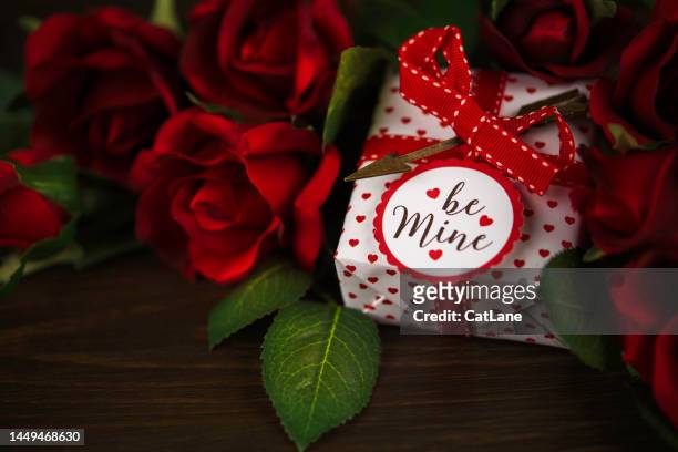 valentine's day background with red roses and a gift on a rustic wood table - dozen roses stock pictures, royalty-free photos & images