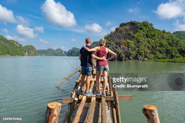 man and woman exploring a wooden walkway in the tropical paradise of cat ba island, vietnam in lan ha & ha long bay in southeast asia - halong bay stock pictures, royalty-free photos & images