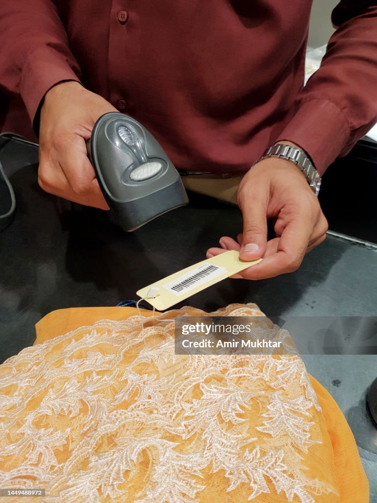 A Salesman Scanning Barcode By Using Barcode Reader In Clothing Store