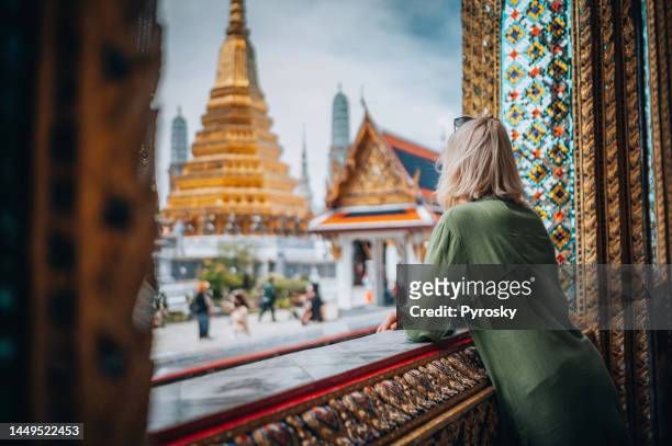 young woman exploring the grand palace in bangkok - wat imagens e fotografias de stock